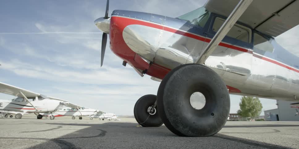 Single engine planes sit at an airport in the daytime