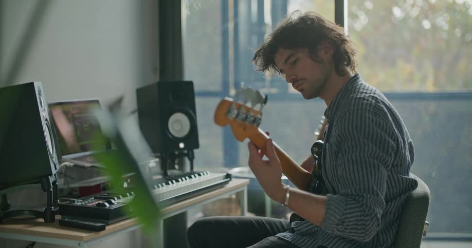 A man playing a bass guitar in a recording studio