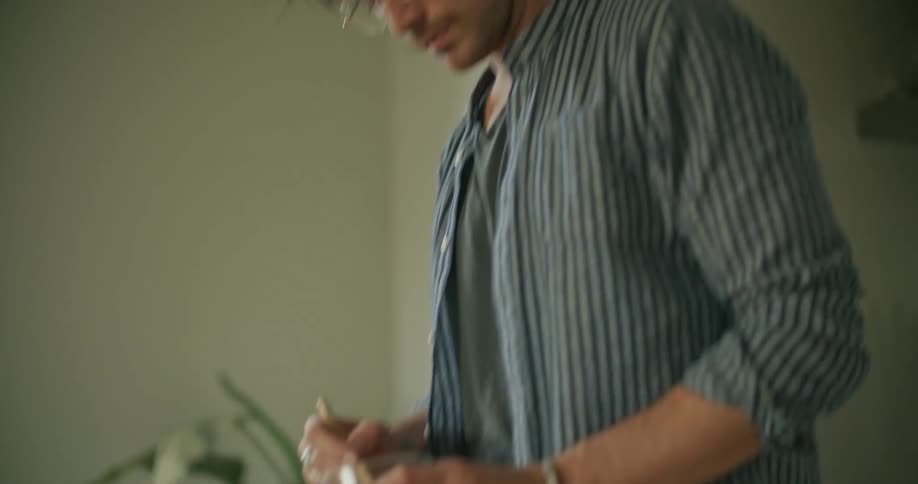 A man is preparing a drink inside of his house