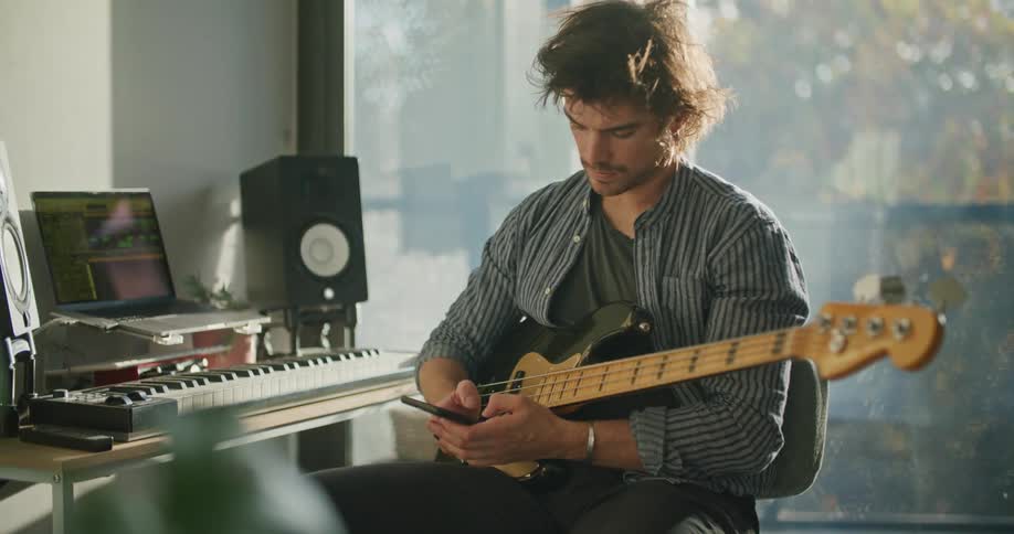 A man is playing guitar and sitting indoors