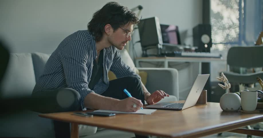 A man is writing and typing at home