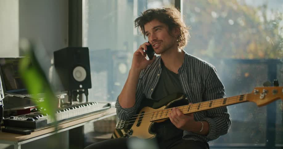 A bass player talking on a phone in a recording studio