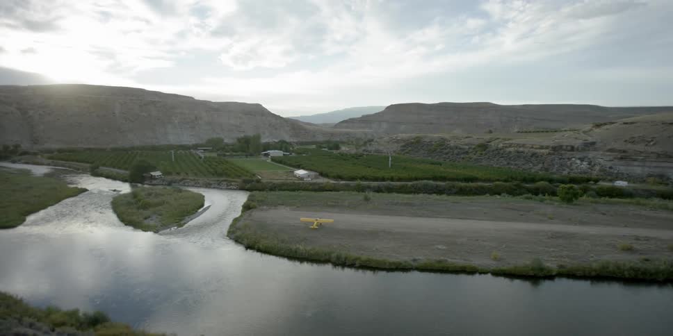 A creek runs by a field with a plane parked