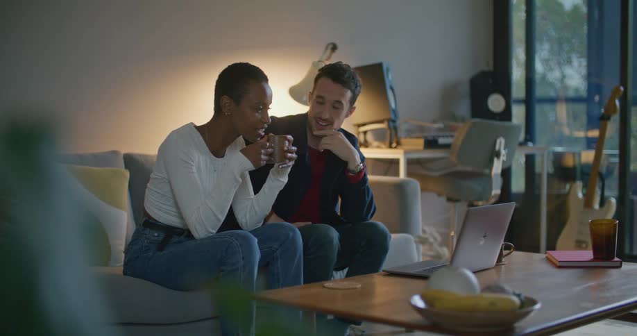 Young couple sitting on the living room talking in front of a laptop over the coffee table