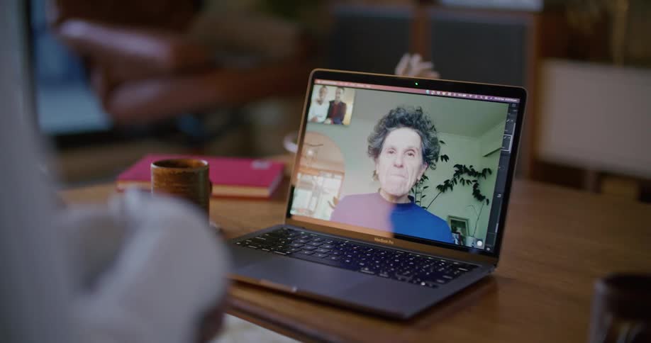 Woman speaking on a video conference on a laptop over a coffee table