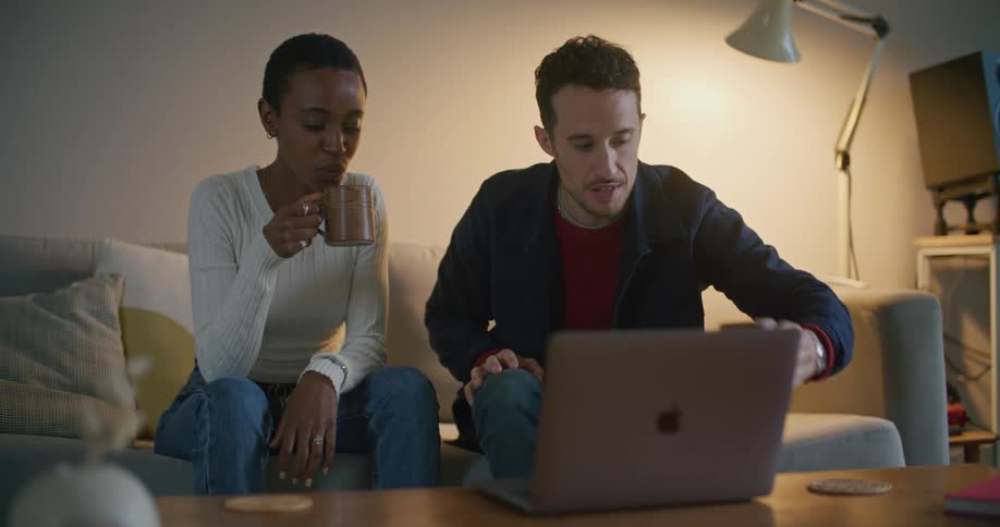 Young couple sitting on the living room talking in front of a laptop over the coffee table