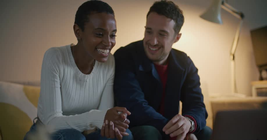 A man and woman smiling while waving and video chatting on a laptop
