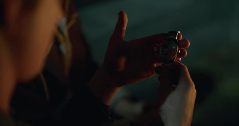 A father giving a son his wristwatch outside next to a bonfire at night
