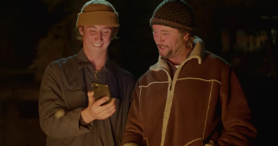 Two people looking at something on a smartphone next to a fire