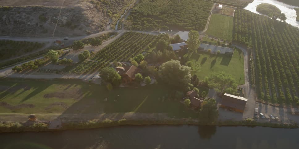 An suv drives on a road to a villa with a vineyard and near river