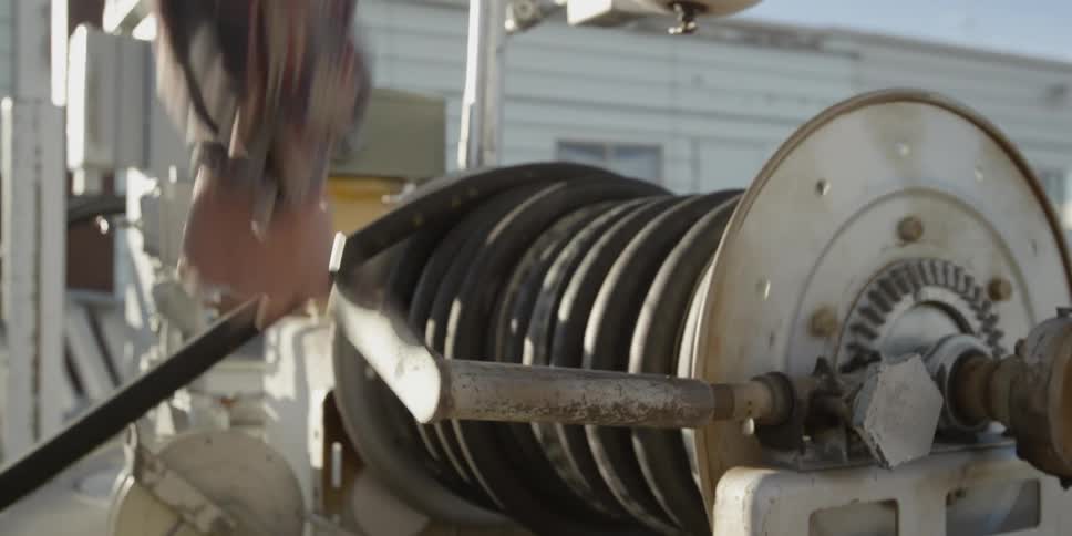 A man is turning a lever to coil a hose