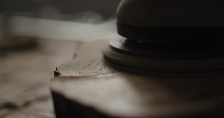 A buffing machine smooths the surface of a piece of wood and then a hand touches the surface