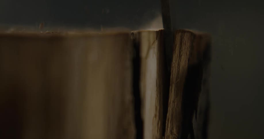 A person in a room chiseling the bark off a log