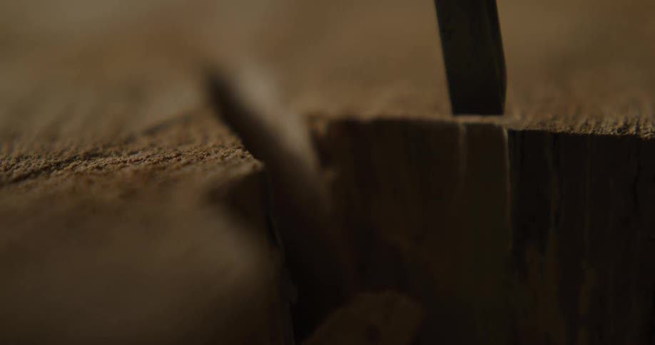 A person in a room using a hammer and chisel on wood
