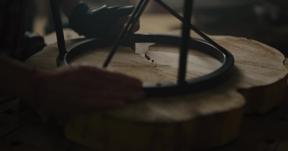 A person in a room placing a metal stand on a piece of wood on a table