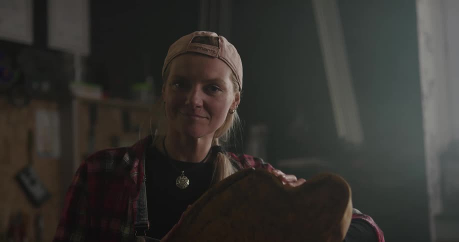 A woman in a room with a hat and a piece of wood with a wall in the background