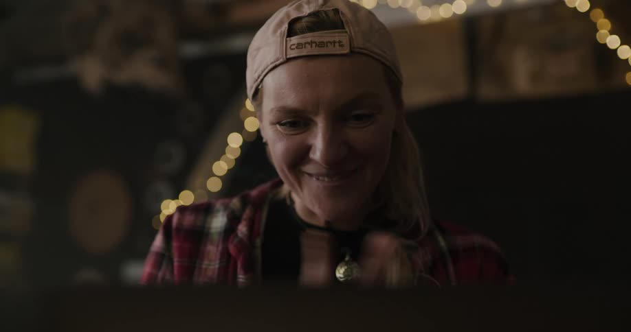 A woman in a room with a hat smiling with a wall in the background