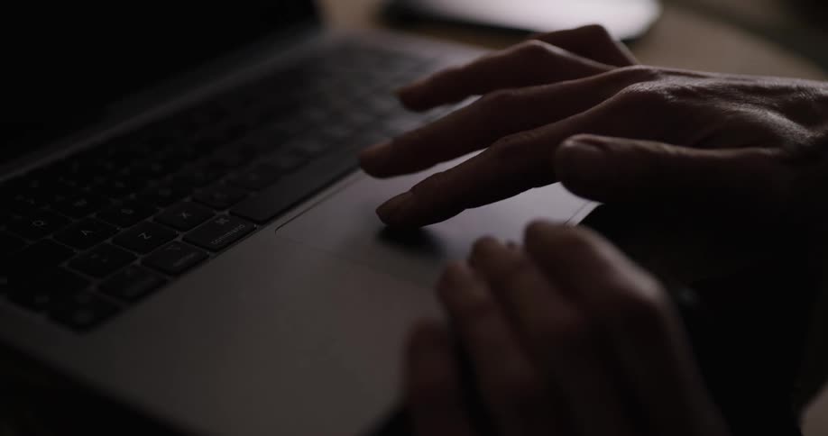 Close up of a womans hands as she uses a keyboard on a laptop