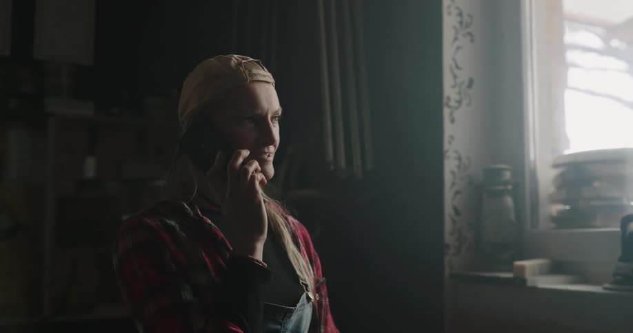 A woman at home smiles as she talks on her cell phone