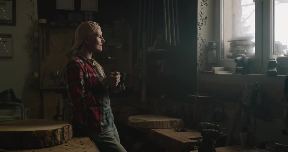 A woman drinking coffee from a mug while gazing out a window