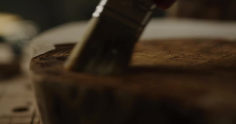Stain being poured on a tree trunk and then brushed on