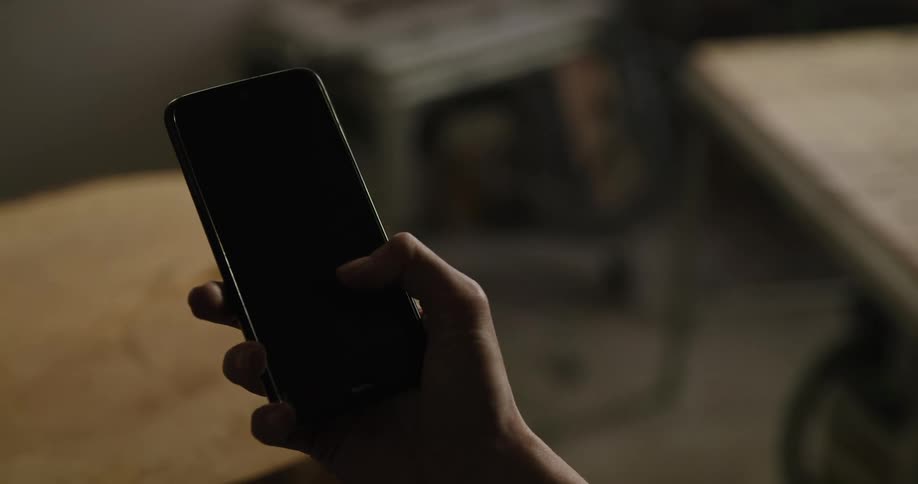 A woman holds a cell phone in her hand and then touches the screen