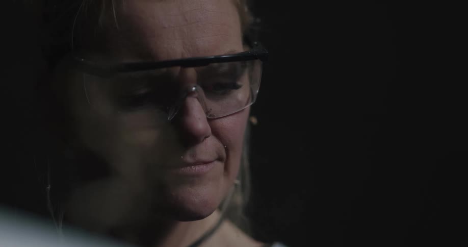 A woman wears goggles to protect her eyes from sawdust flying up