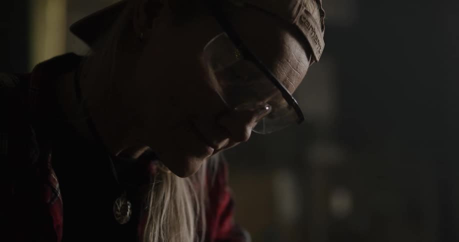 A woman sanding a piece of wood in a shop