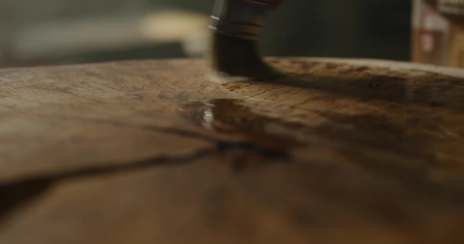 A person painting a piece of wood with stain