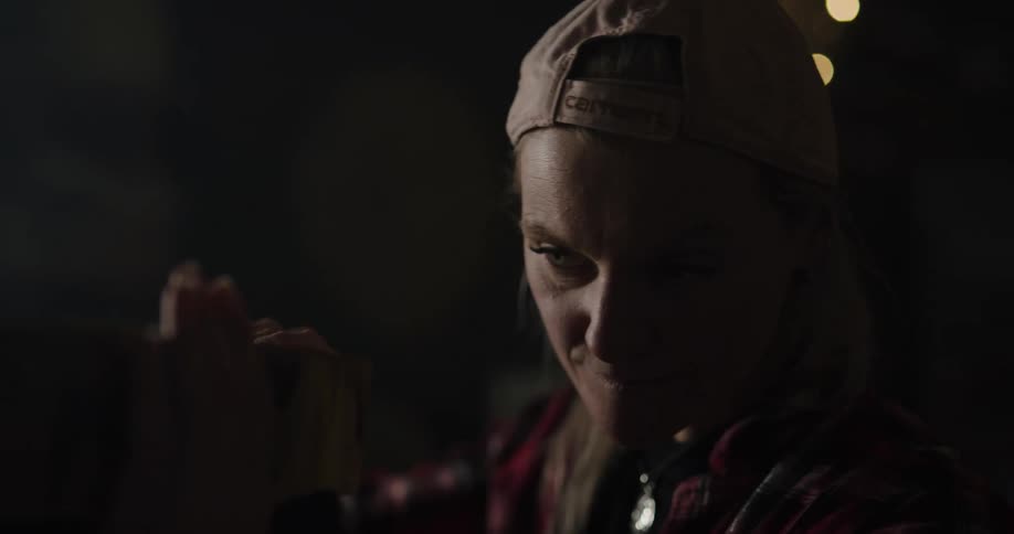 A woman with a hat in a room rubbing a piece of wood with her hands