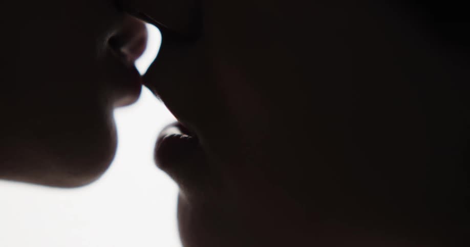 A man and a woman kissing and smiling with a window in the background