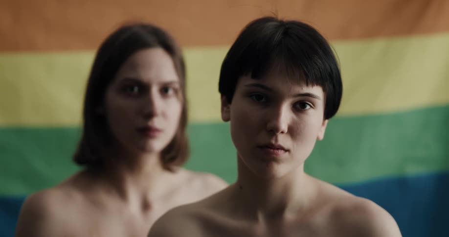 Two teenage girls naked in front of a flag