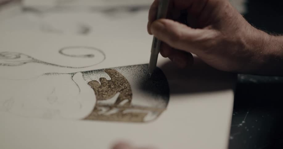 A person holding a pen uses it to apply shading to a drawing that they are doing on canvas