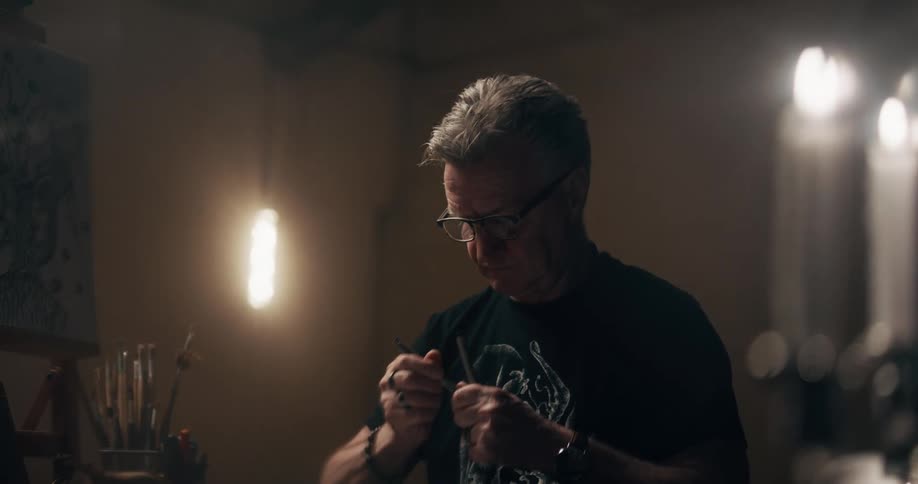 An artist drawing by candlelight in a dark room