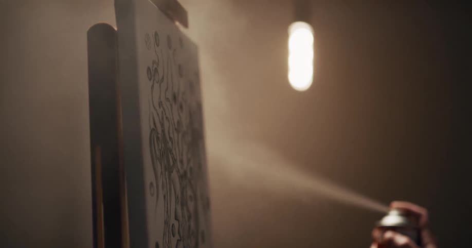 A person spraying an oil painting over an easel