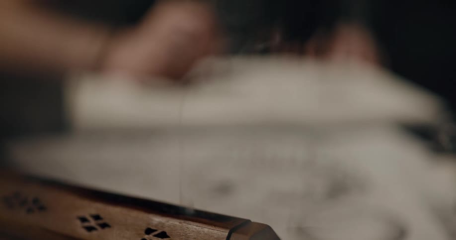 A person sitting at a table drawing near a wood machine that is smoking