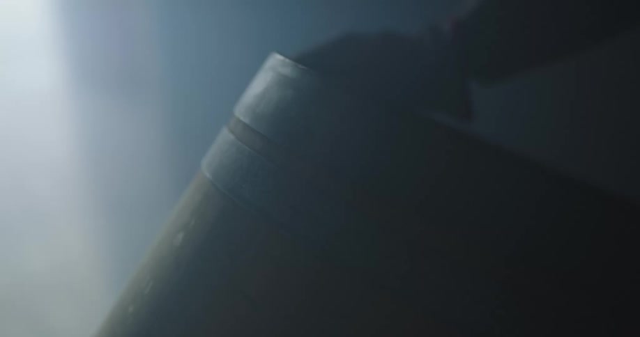 A person with gloves rolling a barrel