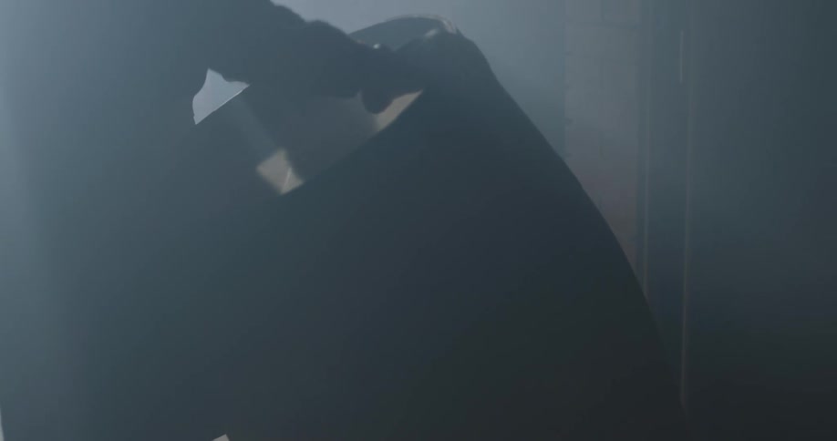 A person opens the door to a dark room and rolls a barrel inside