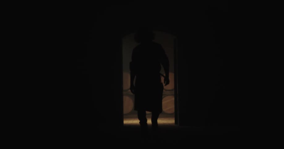A man walks past barrels in a storage area