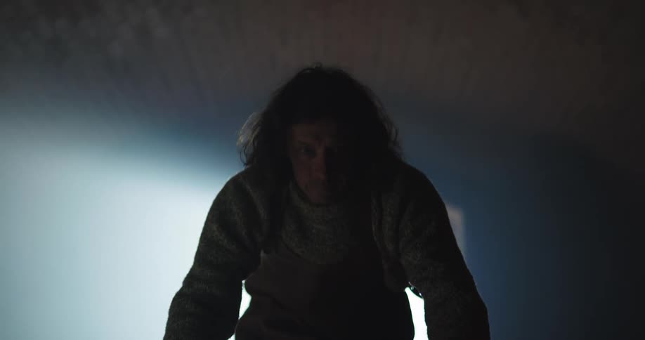 Silhouette of a woman pushing a wooden barrel on a dark hallway