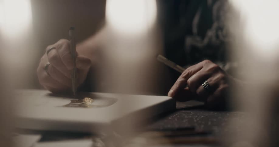 Artist wearing multiple rings dabs ink onto surface