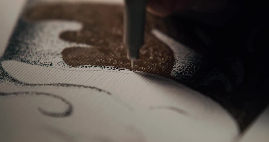 A person holding a pen making a design on an art canvas