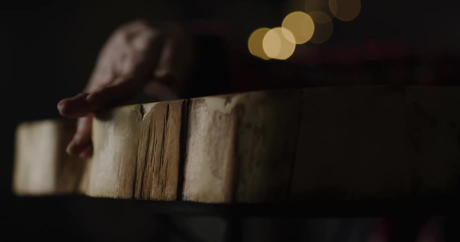 A woman in a room rubbing a wooden table with her hand