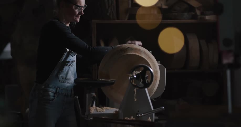 A woman working on a lathe in a shop
