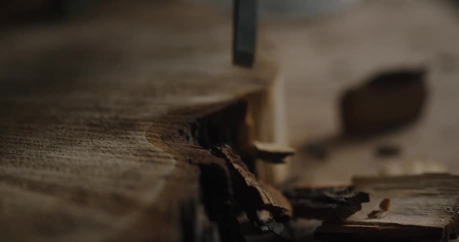 A person is using a knife to cut pieces of wood