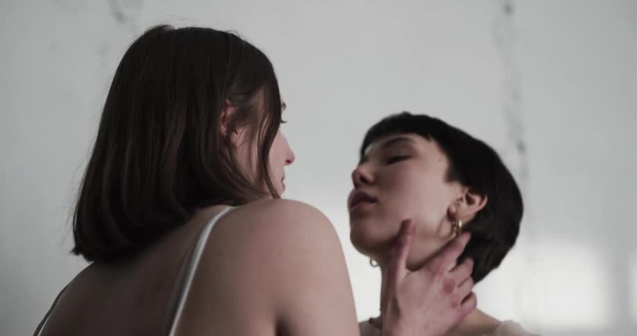 Lesbian couple hugging and almost kissing inside a room