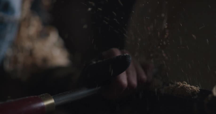 Sawdust flies as a woman sands