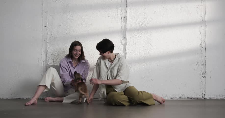 Two women that are playing with a puppy