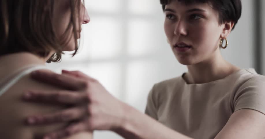 Two teenage girls look at one another and start to remove their clothing and lean in for a kiss