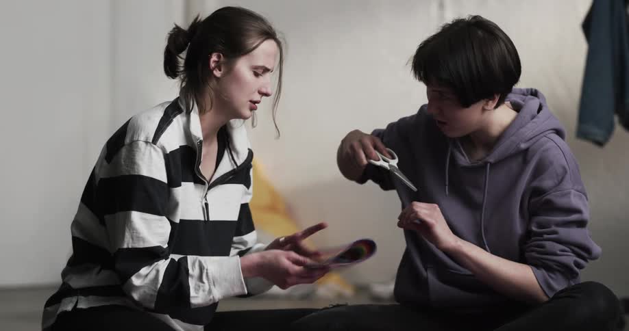 Two women doing a craft project with fabric and scissors while sitting on the floor